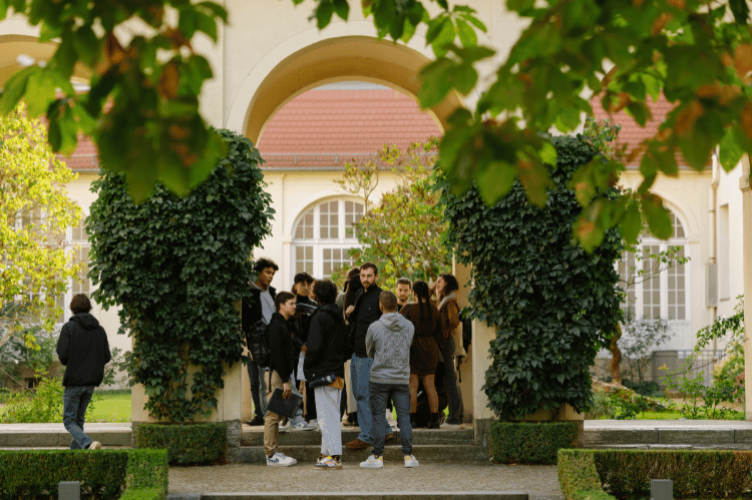 A group of students standing outside near a garden